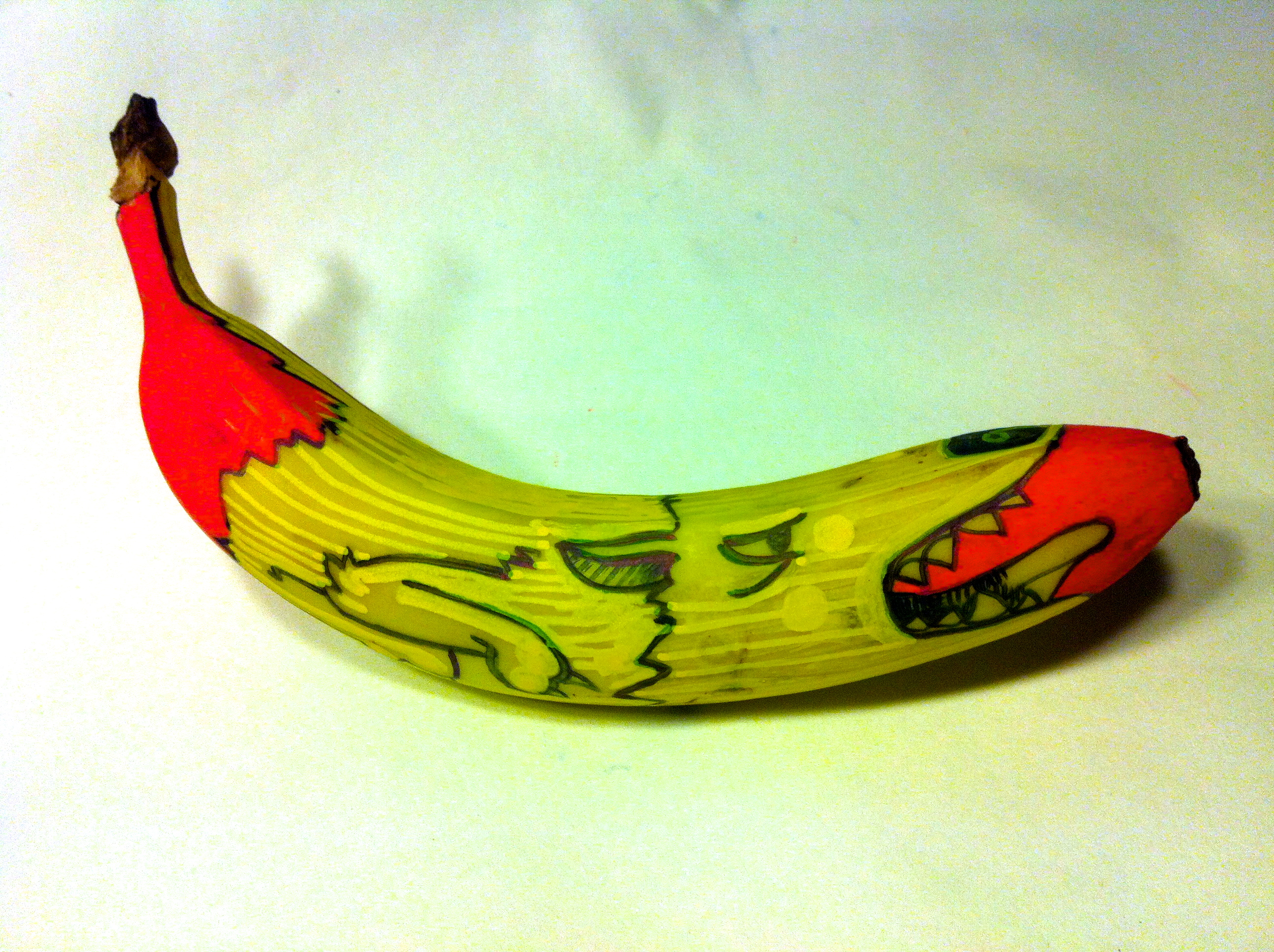 Painted banana, a dog monster sticks it's tongue out on a red background. 