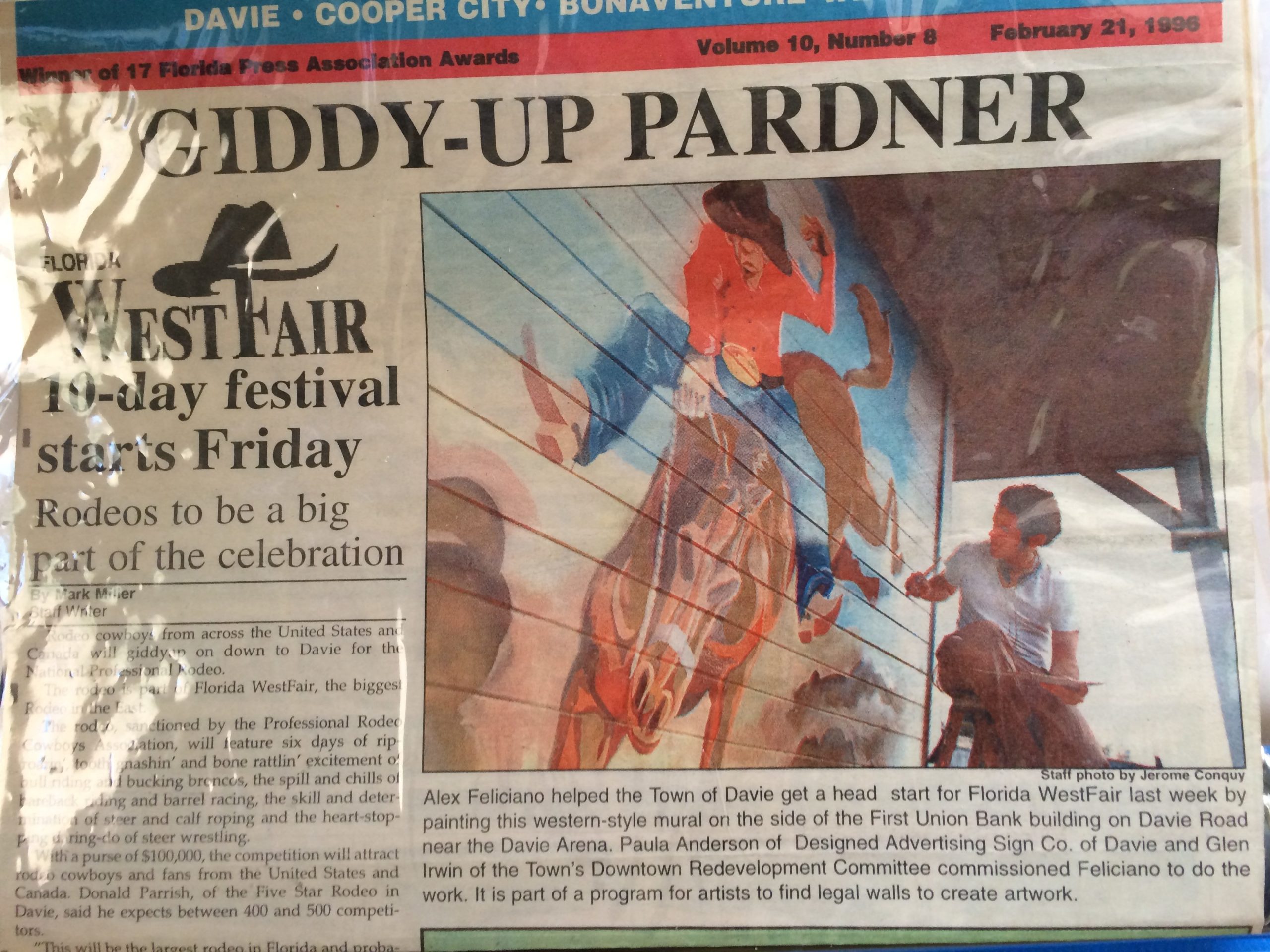 A news paper article where, Alex Feliciano is pictured painting a mural. The city of Davie, Fl. News paper from February 21,1996.